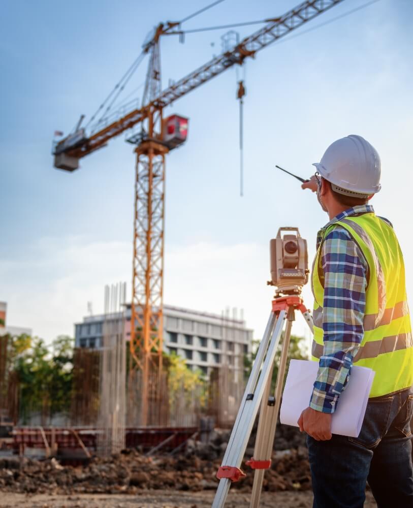 Ein Mann mit Schutzhelm und Warnweste steht vor eine Baustelle