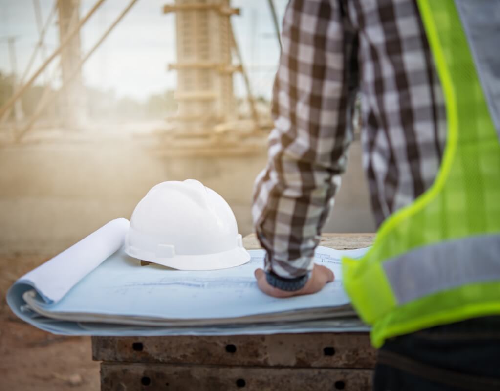 Ein Bauarbeiter steht vor einem Bauplan auf einer Baustelle
